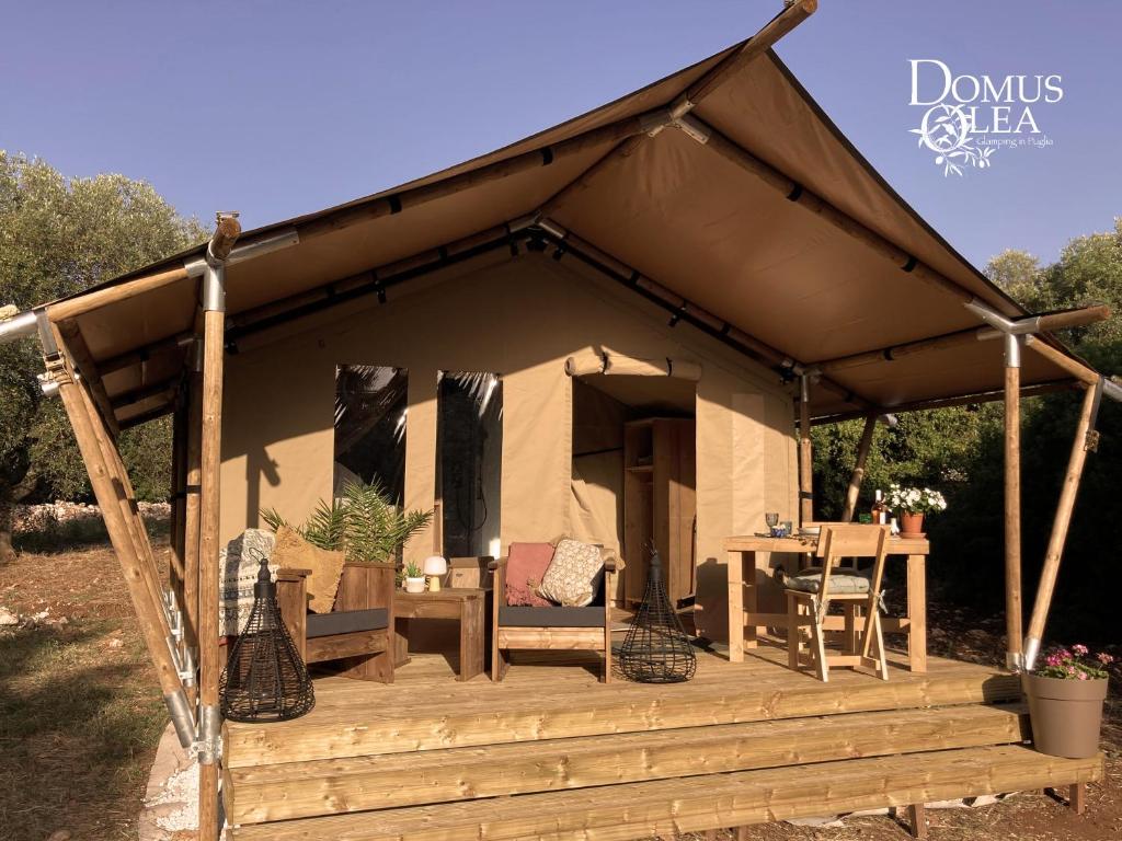 a tent with a wooden deck with a table at Domus Olea Glamping in Ceglie Messapica