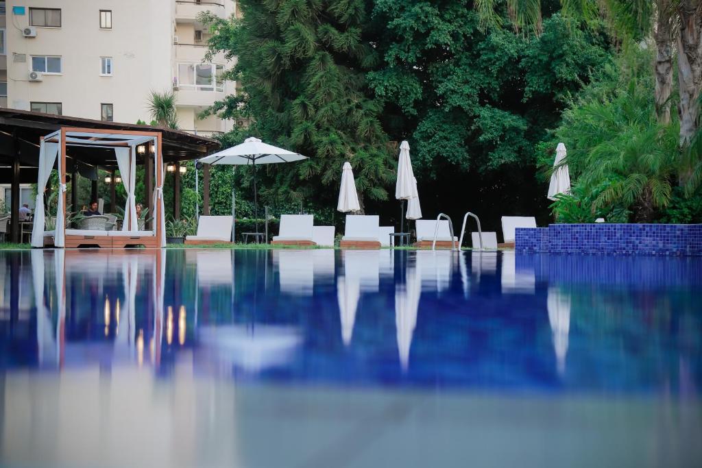 a swimming pool with white chairs and an umbrella at Odysseia Hotel Kapetanios in Limassol