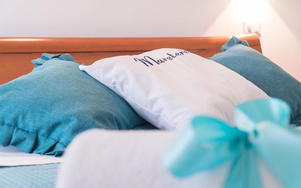 a bed with blue pillows and a white pillow with a blue bow at Mareterè in Vietri sul Mare