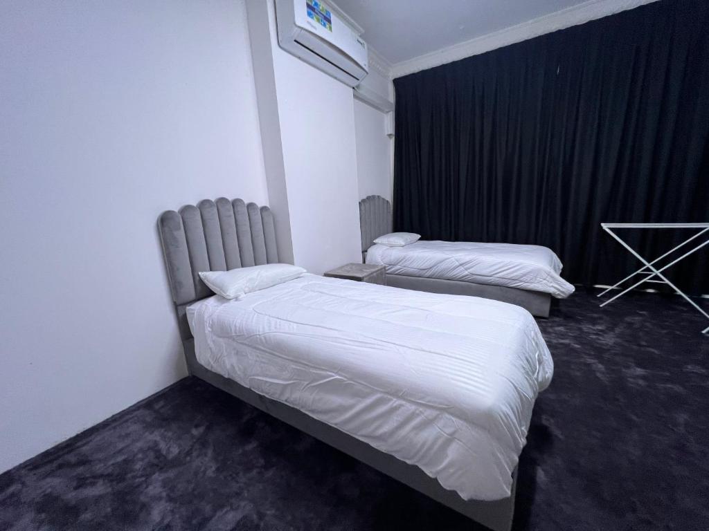 2 camas en una habitación de hotel con sábanas blancas en Dinar apartments - twin bed, en Abu Dabi