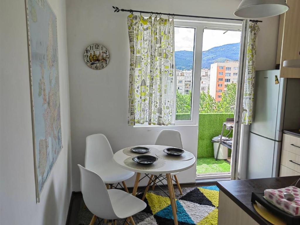 una pequeña cocina con mesa, sillas y ventana en Alexander Apartments Kyustendil en Kyustendil