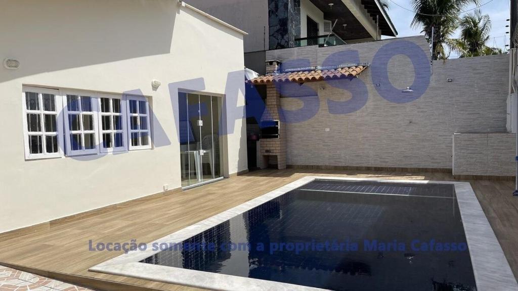 uma piscina em frente a uma casa em CASA PÉ NA AREIA COM PISCINA A 10mts ENSEADA no Guarujá