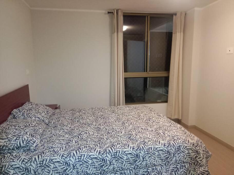 Un dormitorio con una cama azul y blanca y una ventana en Comodo y divertido espacio, en Antofagasta
