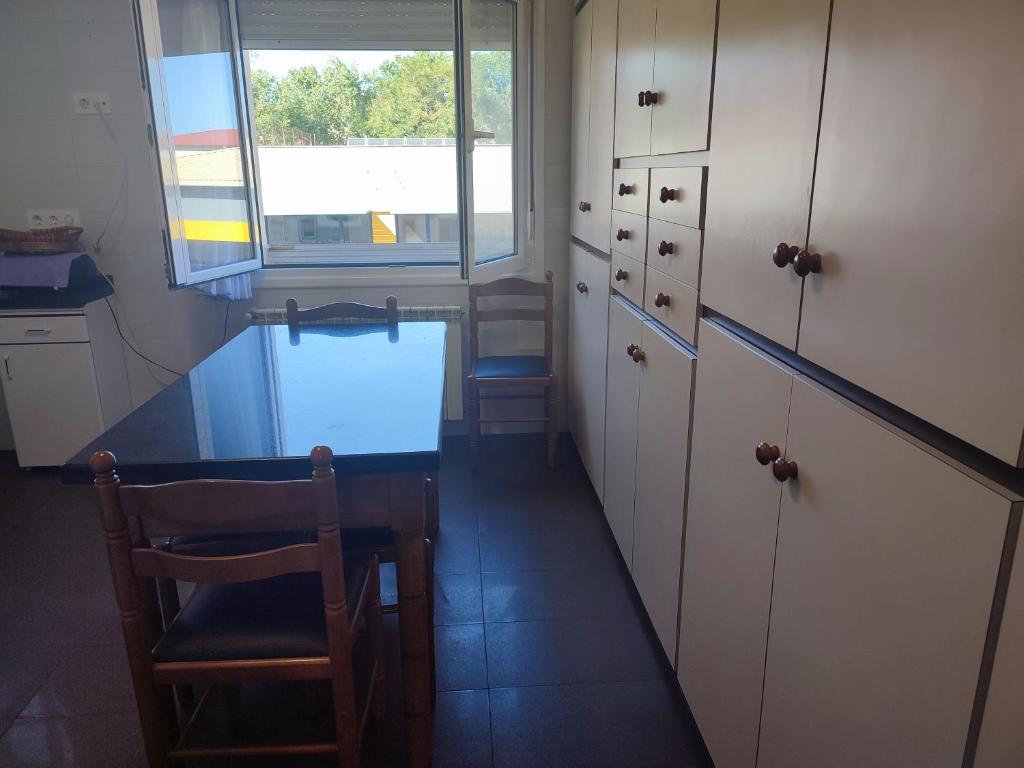 ヒホンにあるPrecioso piso en Gijónのキッチン(テーブル、椅子付)、窓が備わります。