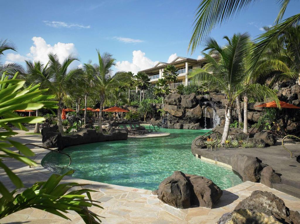 - une piscine dans un complexe avec une cascade et des palmiers dans l'établissement Ho'olei at Grand Wailea, à Wailea
