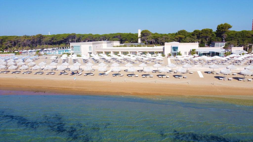 uma praia com muitas cadeiras e guarda-sóis em Riviera Resort Hotel em Lignano Sabbiadoro