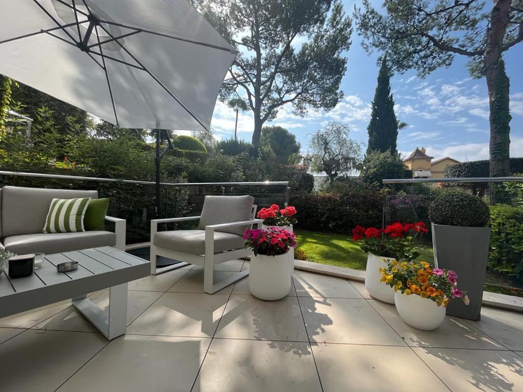 - une terrasse avec des chaises, un parasol et des fleurs dans l'établissement Modern villa in gated complex Sierra Blanca Marbella, à Marbella