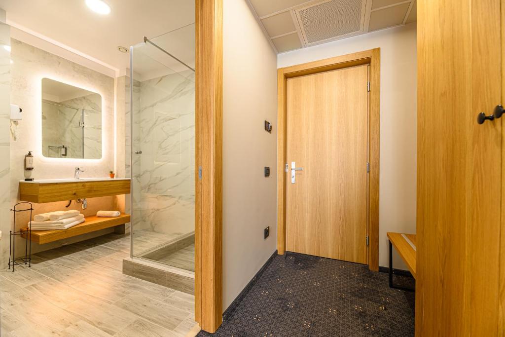 a bathroom with a walk in shower and a glass door at Hotel DUKAT in Gura Humorului