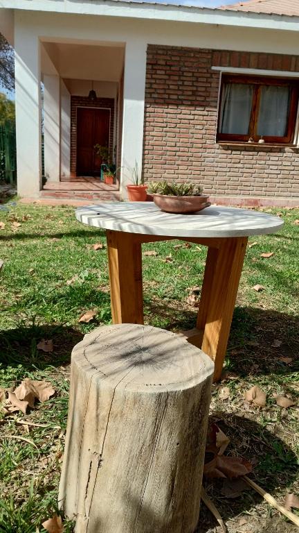 una mesa de madera con un tronco de árbol frente a una casa en Casa Oliva en Cafayate