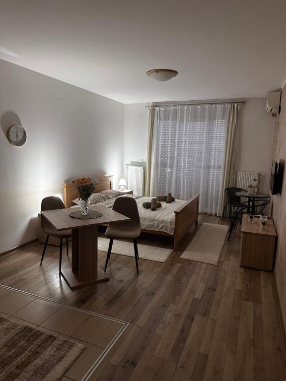 a bedroom with a bed and a table and chairs at Apartman San in Ruma