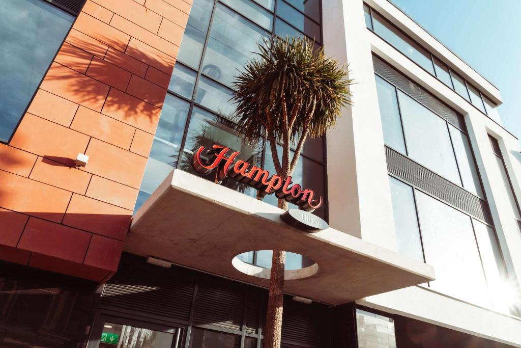 a sign on the side of a building with a palm tree at Hampton By Hilton Torquay in Torquay