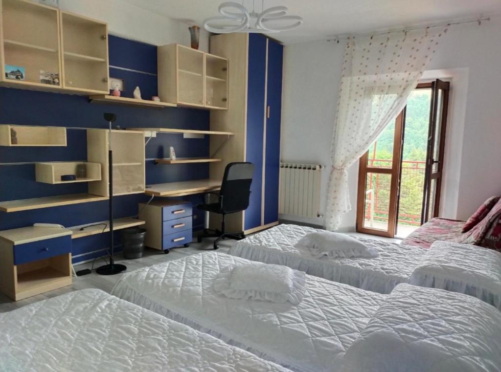 une chambre avec deux lits et un bureau et une fenêtre dans l'établissement Camera mezzo montagna, à San Bartolomeo