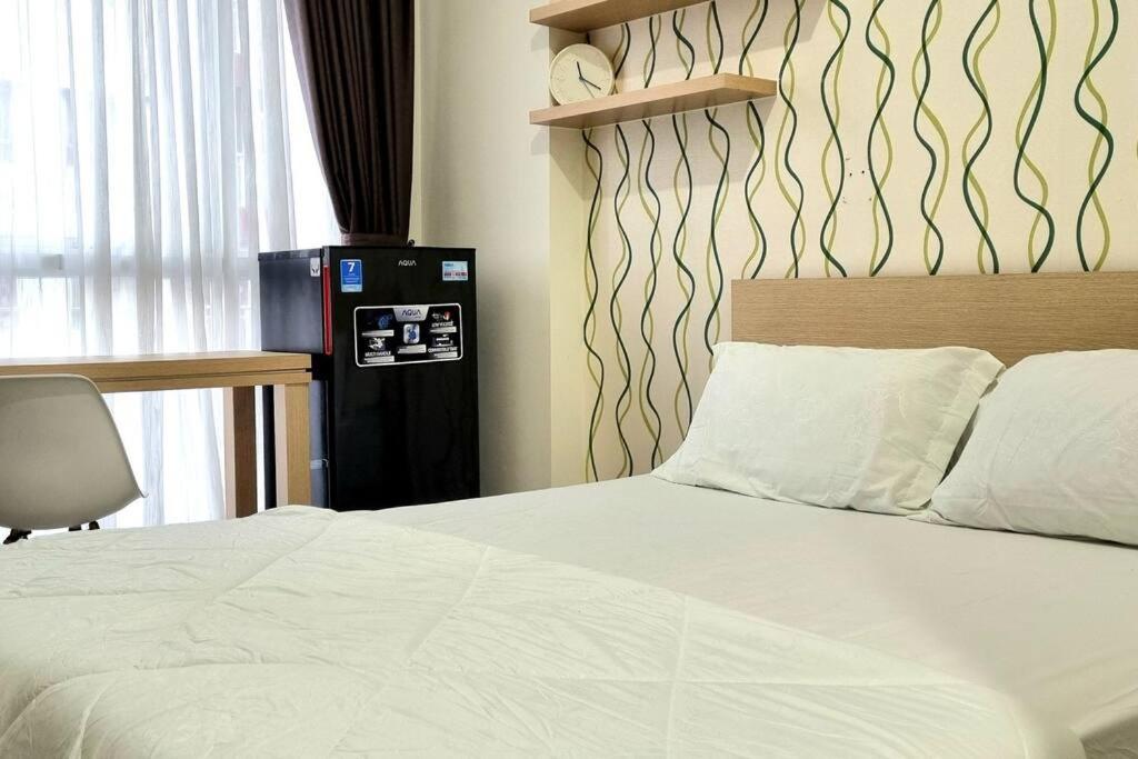a bedroom with a white bed and a chair at Apt Grand Taman Melati 2 Studio UI Depok 4N4 in Pondokcina