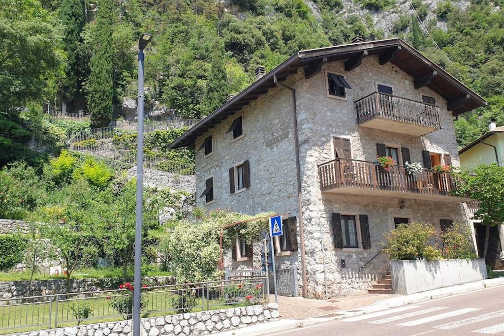 a stone house with a balcony on the side of a street at Dimora Il Vecchio Mulino in Drena