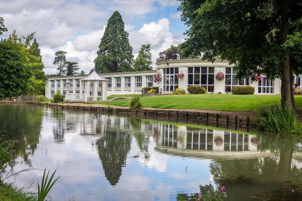 a building with a lake in front of it at DoubleTree by Hilton Cheltenham in Cheltenham