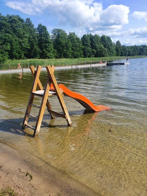 an orange slide in the middle of a body of water at Becejły HILLS in Szypliszki