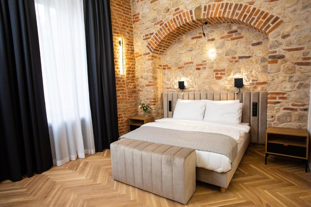 克拉科夫的住宿－HOTEL TEATR，卧室设有一张砖墙内的大床