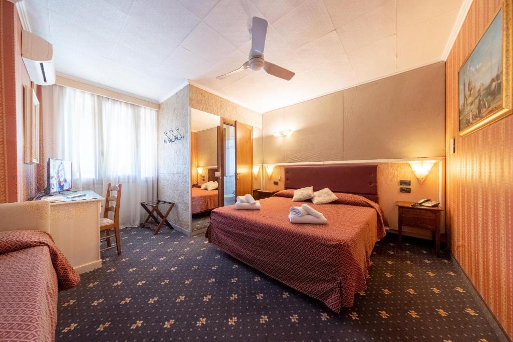 a hotel room with two beds and a desk at Holiday Rooms Antica Badia in Volterra