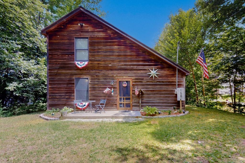 オーガスタにあるThe Three Cornered Pond Retreatの二本のアメリカ旗を掲げた丸太小屋