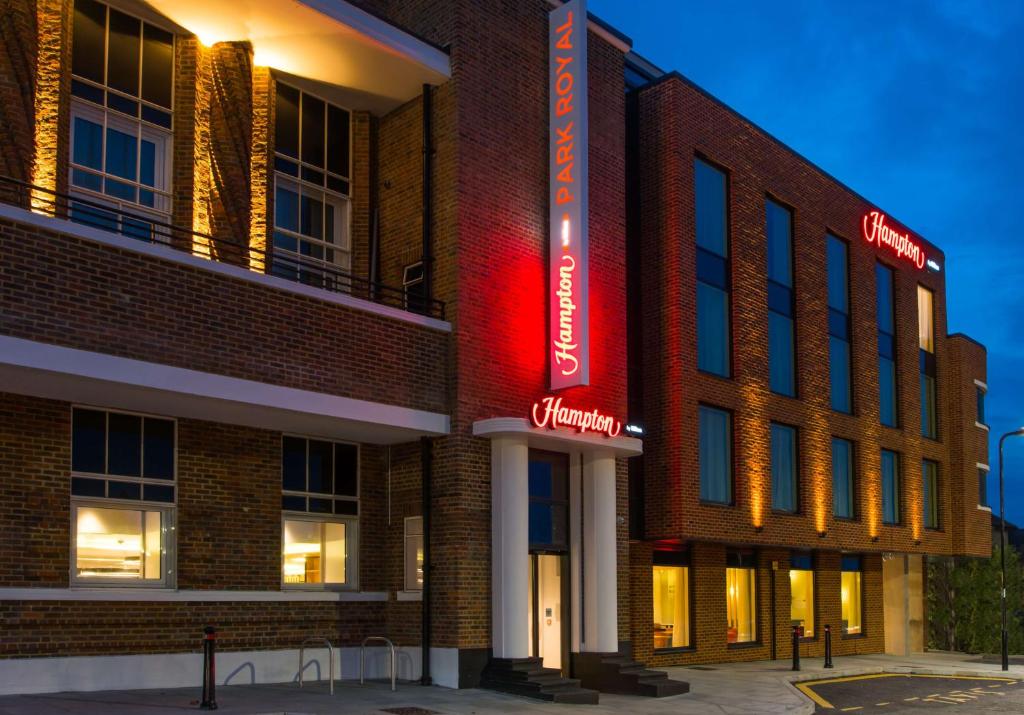 a brick building with a red sign on it at Hampton by Hilton London Park Royal in London