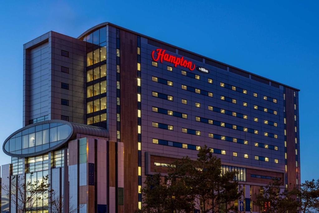 un grand bâtiment avec un panneau de pharmacie sur celui-ci dans l'établissement Hampton by Hilton Liverpool John Lennon Airport, à Speke