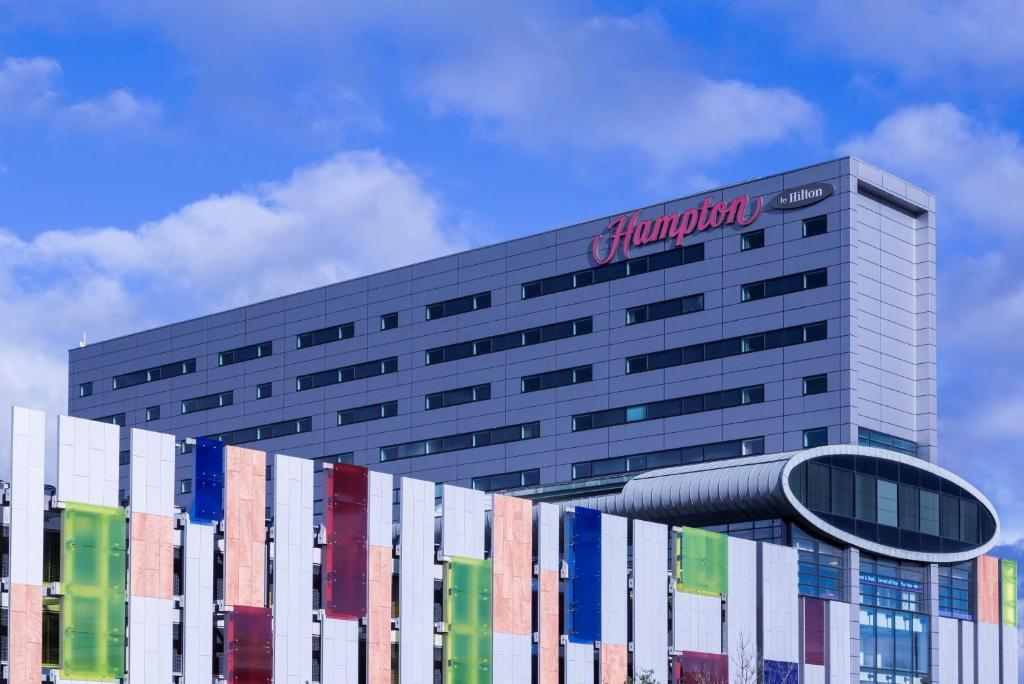 a building with a sign on the side of it at Hampton by Hilton Liverpool John Lennon Airport in Speke