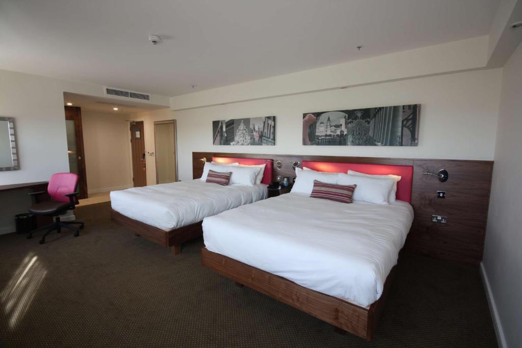 a hotel room with two beds and a desk at Hampton by Hilton Liverpool John Lennon Airport in Speke
