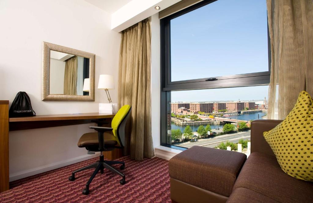 una camera con divano, scrivania e ampia finestra di Hampton By Hilton Liverpool City Centre a Liverpool