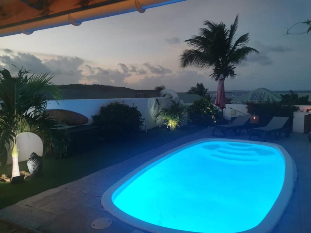 a swimming pool in a backyard at night at VILLA PELICAN in Oyster Pond