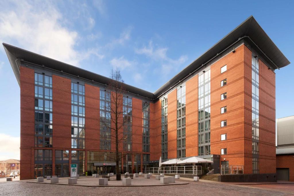 a large red brick building with a black roof at Hilton Garden Inn Birmingham Brindley Place in Birmingham