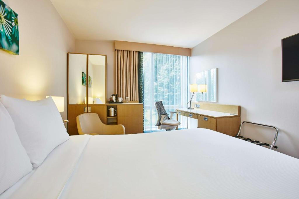 a hotel room with a large white bed and a desk at Hilton Garden Inn Birmingham Brindley Place in Birmingham