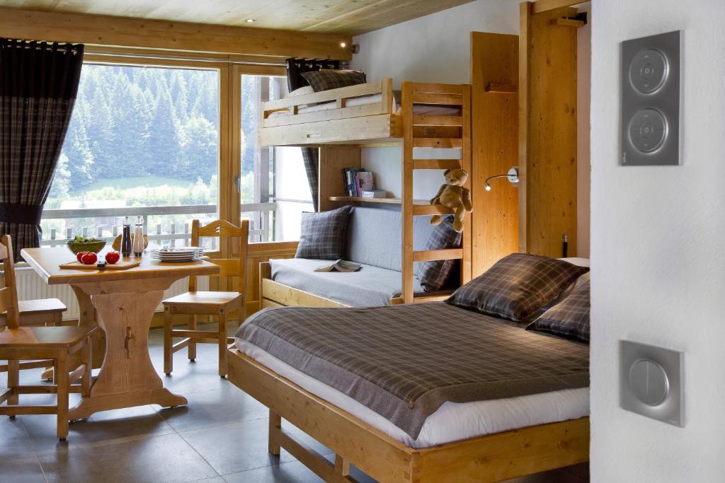 a bedroom with a bunk bed and a table and a desk at Studio Danay Accès Espace Détente Gratuit in Le Grand-Bornand