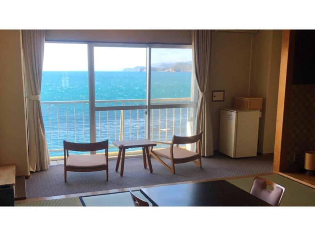 Zimmer mit einem Tisch und Stühlen sowie einem großen Fenster in der Unterkunft Seaside Hotel Geibousou - Vacation STAY 92572v in Shima