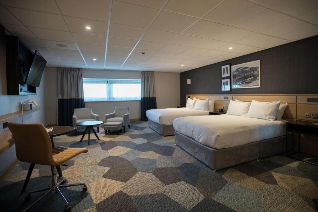 a hotel room with two beds and a table and chairs at DoubleTree by Hilton Coventry Building Society Arena in Coventry