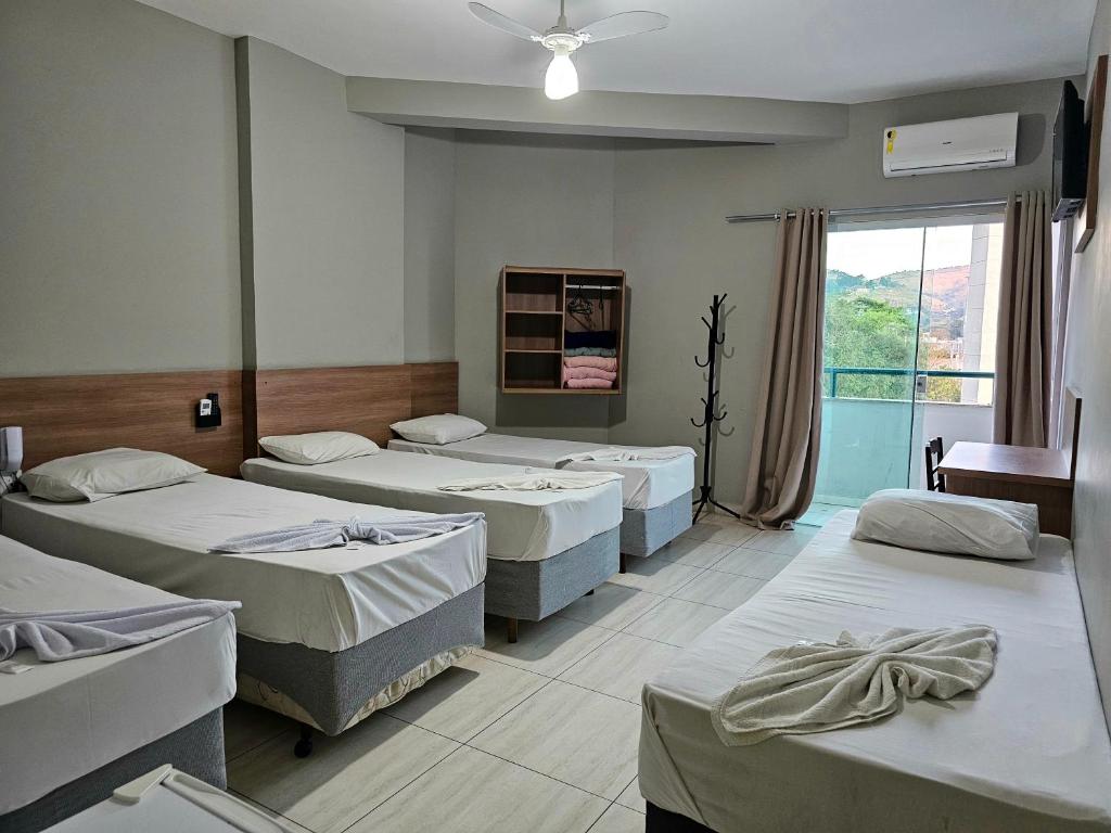 a room with four beds and a window at MAPP Hotel Aparecida-SP in Aparecida