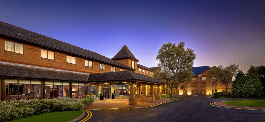 un gran edificio de ladrillo con un árbol delante de él en DoubleTree by Hilton Sheffield Park, en Sheffield