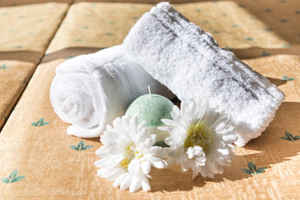 a roll of towels and white flowers on a table at Apartaments Condado by Marsol in Lloret de Mar