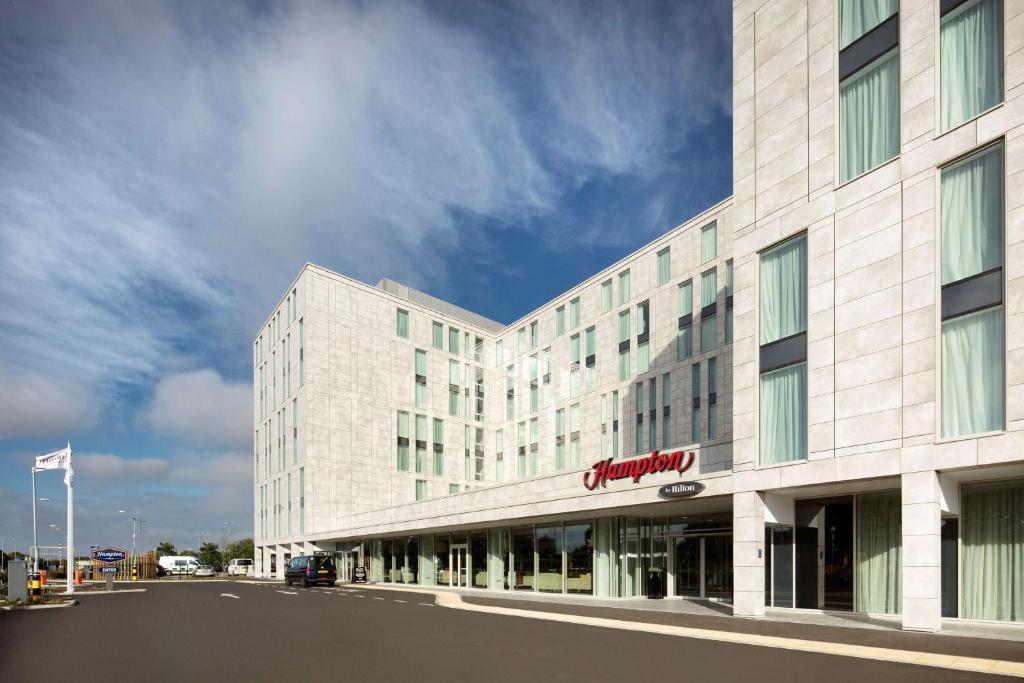 a large white building with a sign on it at Hampton By Hilton London Stansted Airport in Stansted Mountfitchet