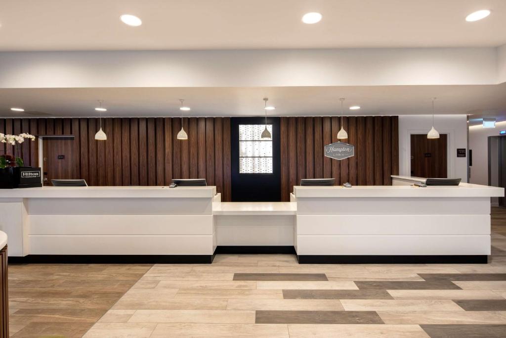 a lobby with a waiting area with white counters at Hampton By Hilton London Stansted Airport in Stansted Mountfitchet