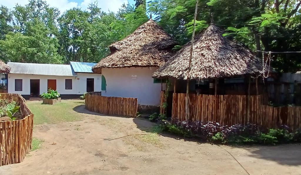 a house with thatched roofs and a fence at Omnia Resort in Mtwapa
