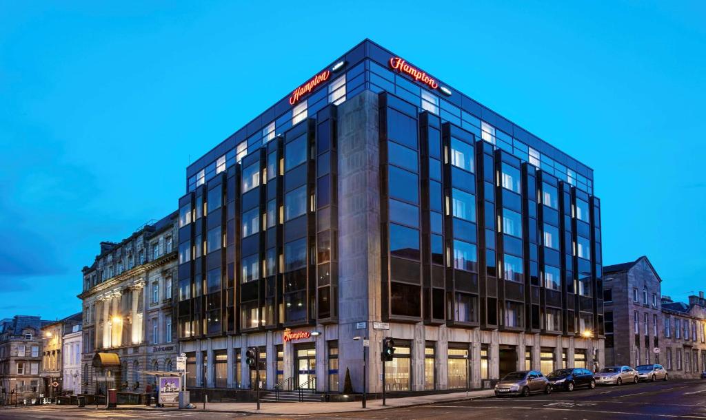 un bâtiment dans une rue avec des voitures garées devant elle dans l'établissement Hampton by Hilton Glasgow Central, à Glasgow