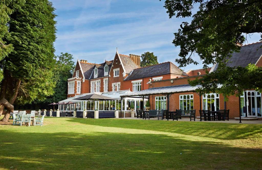 un grande edificio in mattoni con un prato di fronte di DoubleTree by Hilton St. Anne's Manor a Bracknell