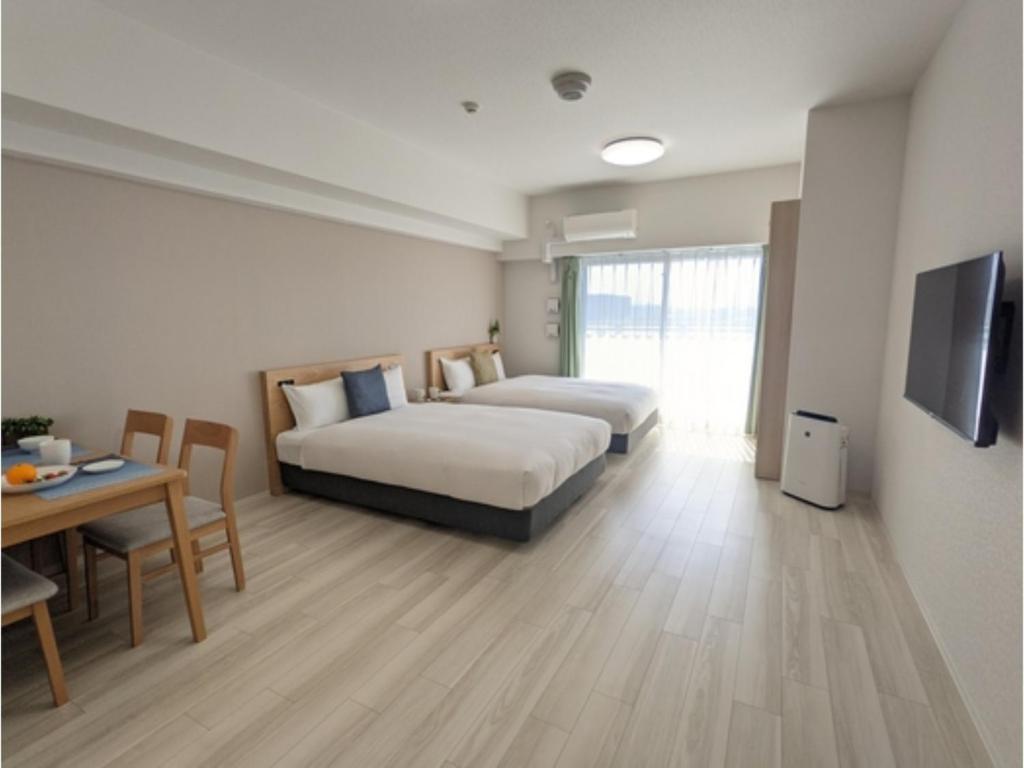 um quarto de hotel com duas camas e uma mesa e uma televisão em ESLEAD HOTEL Namba Daikokucho - Vacation STAY 86023v em Osaka