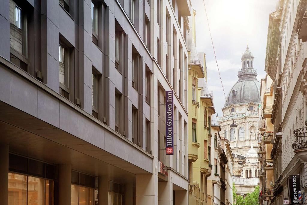 a city street with tall buildings and a cathedral at Hilton Garden Inn Budapest City Centre in Budapest