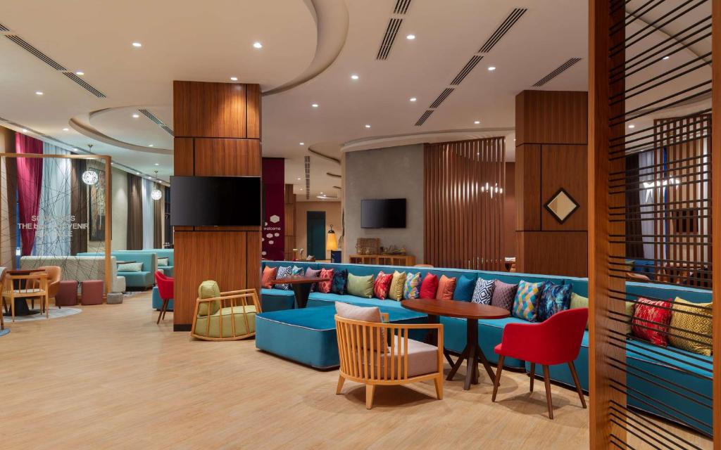 vestíbulo con sofá azul, mesas y sillas en Hampton By Hilton Turkistan en Türkistan