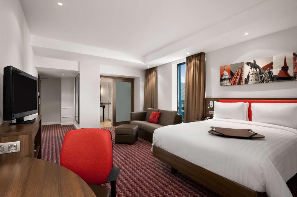 a hotel room with a bed and a desk and a tv at Hampton by Hilton Cluj-Napoca in Cluj-Napoca