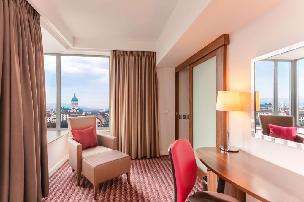 a hotel room with a desk and chair and a window at Hampton by Hilton Cluj-Napoca in Cluj-Napoca