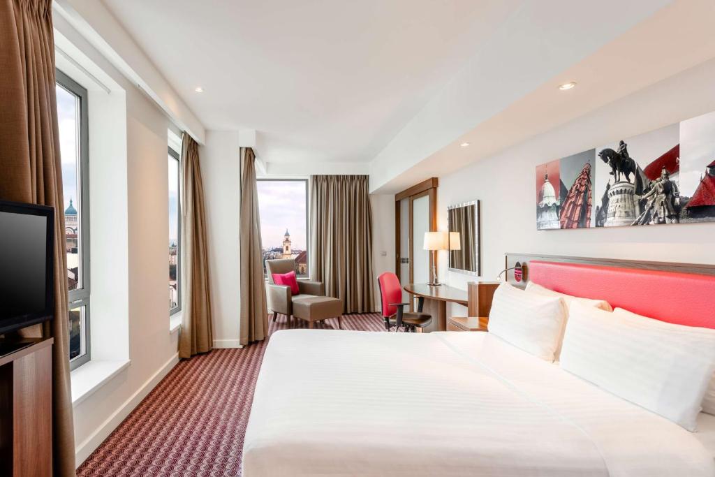 a hotel room with a large bed and a desk at Hampton by Hilton Cluj-Napoca in Cluj-Napoca