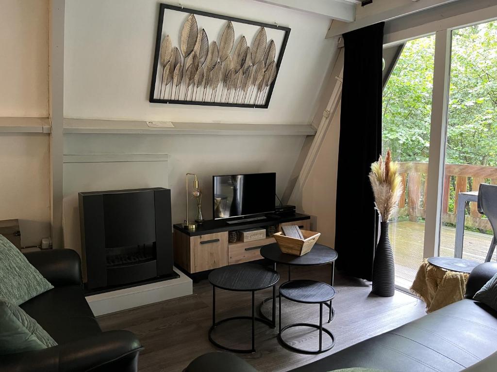 uma sala de estar com um sofá e uma televisão e cadeiras em Chalet 177 Durbuy em Durbuy