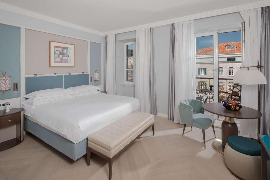 a bedroom with a white bed and a table and chairs at Hilton Imperial Dubrovnik in Dubrovnik
